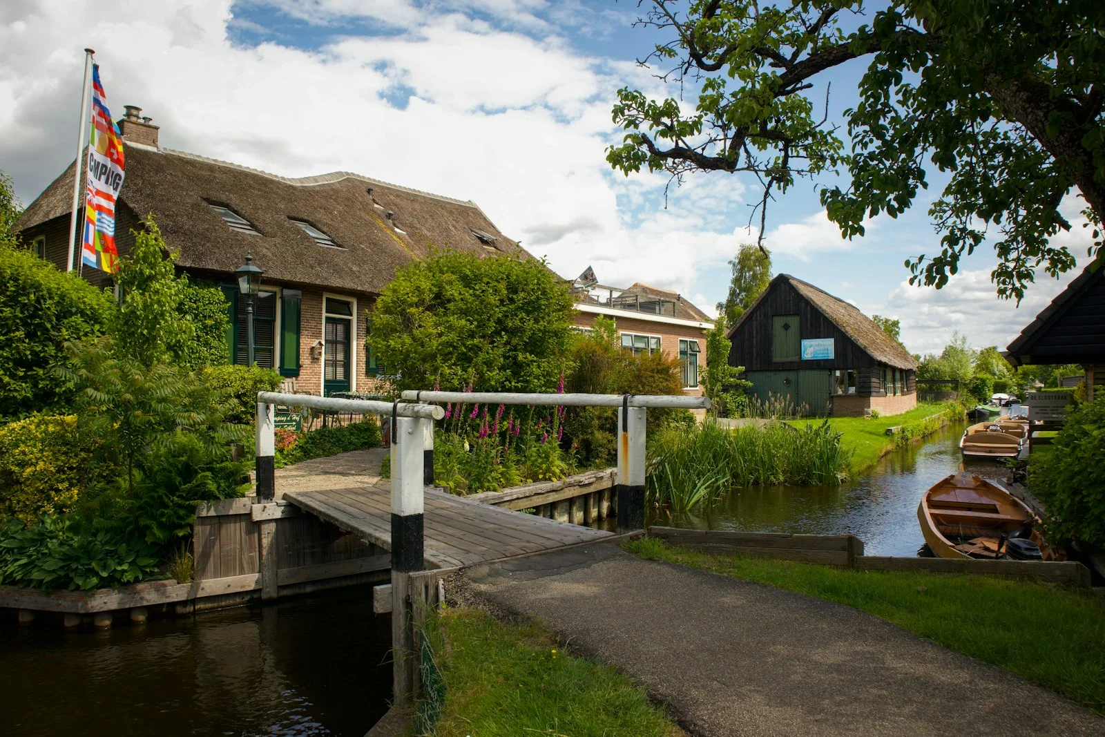 Maisons aux toits de chaume et pont piétonnier au bord d'un canal de Giethoorn