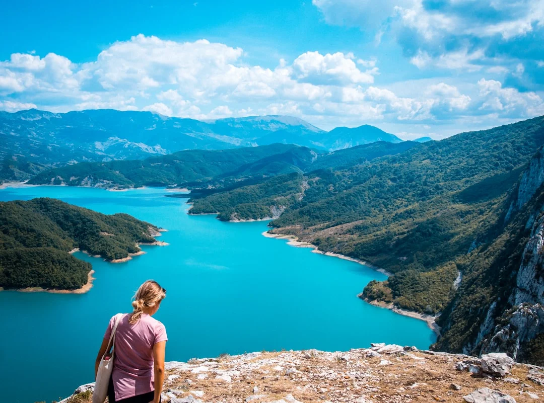 Randonneuse debout au sommet d'une montagne des Alpes albanaises au-dessus d'un lac de montagne