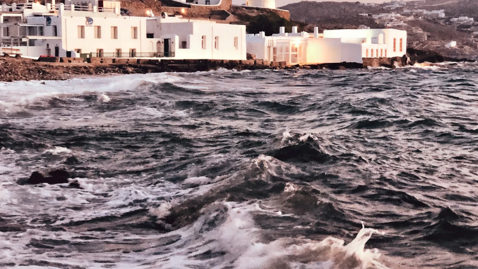Moulins et bâtiments blancs de Mykonos au bord de l'eau à l'heure dorée