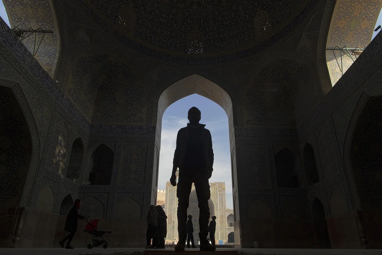 Silhouette of a traveller beneath the monumental iwan of the Shah Mosque in Isfahan, a highlight of a trip to Iran
