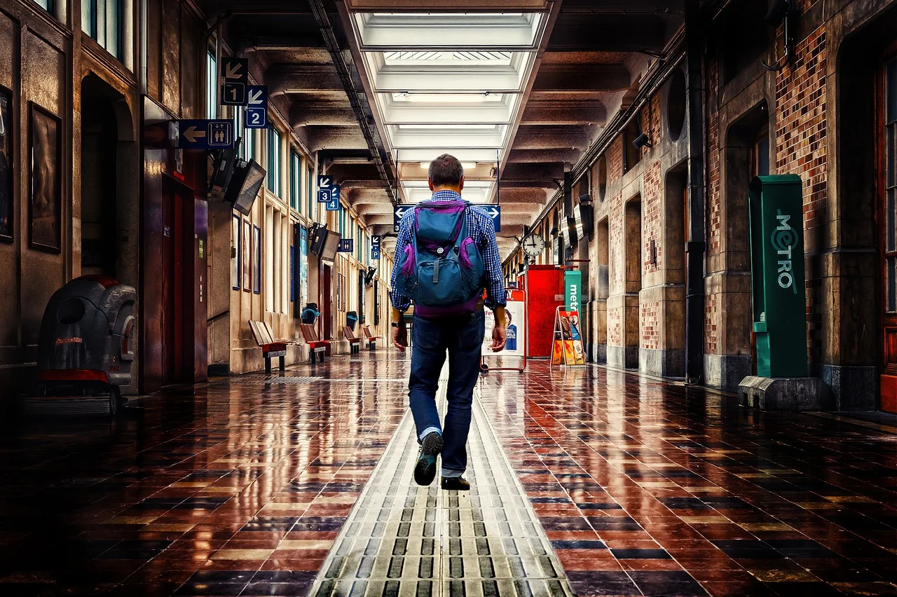 Voyageur avec un sac à dos traversant le couloir d'une gare menant au métro