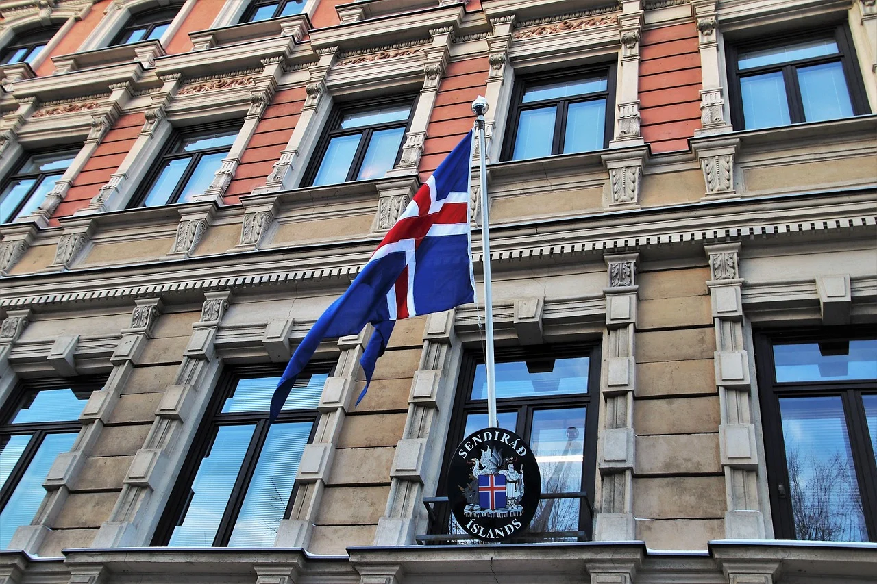 Façade d'un bâtiment diplomatique avec un drapeau hissé au-dessus de l'entrée principale, illustrant une demande de visa déposée en ambassade.