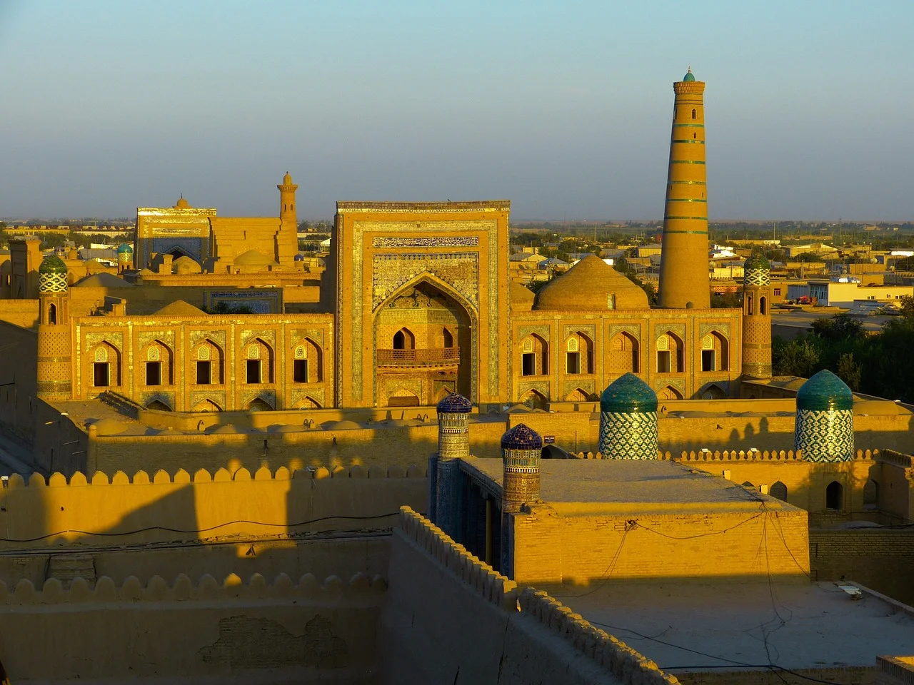 La vieille ville fortifiée de Khiva en Ouzbékistan au coucher du soleil, minaret et coupoles turquoise dominant les toits de brique ocre