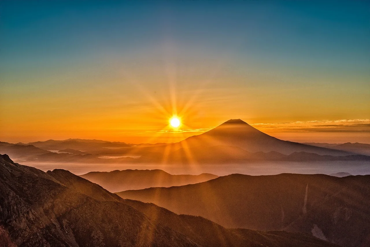 Le mont Fuji au lever du soleil, sa silhouette conique émergeant d'une mer de nuages dans une lumière orangée