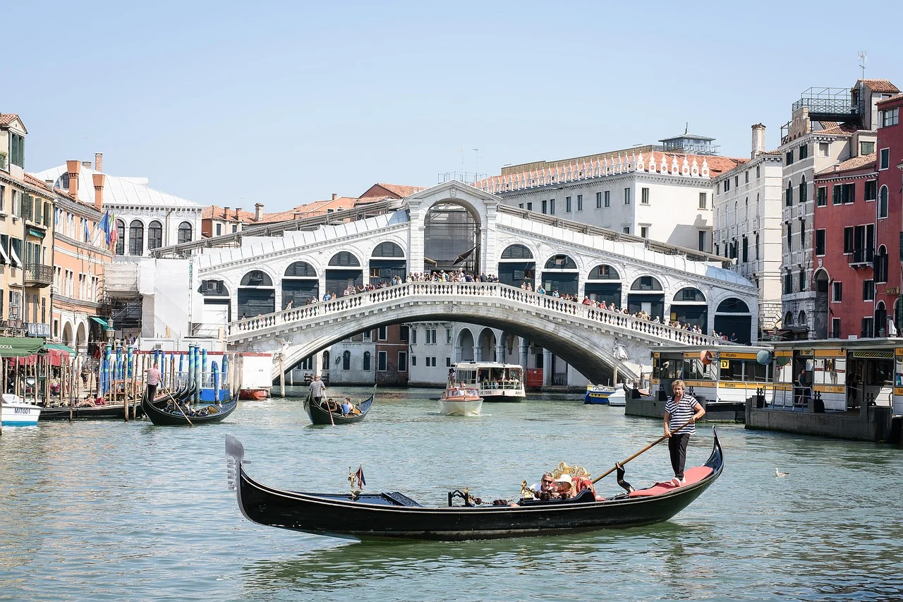 Le pont du Rialto à Venise, ses arcades et son tablier animés de visiteurs, avec des gondoles sur le Grand Canal