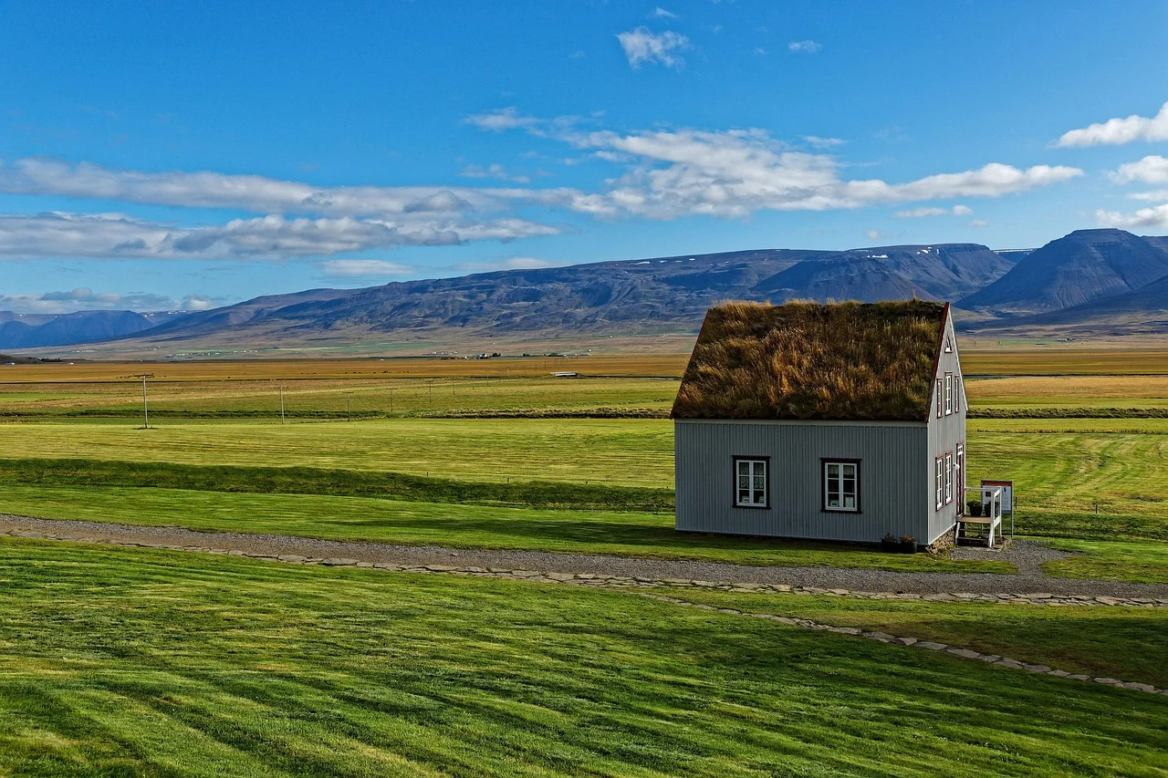 Maison islandaise à toit de tourbe au pied d'un plateau basaltique, le long de la Ring Road