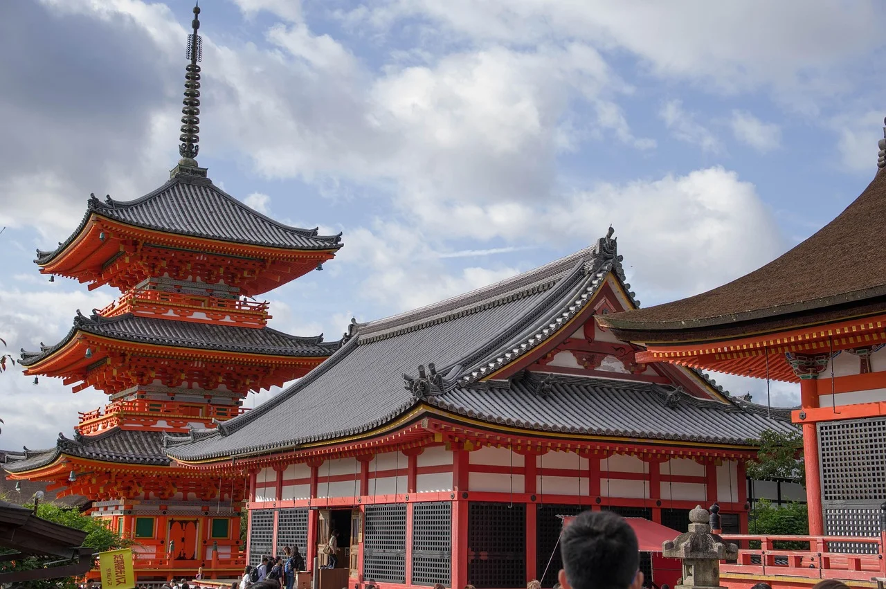 Pagode du temple Kiyomizu-dera à Kyoto entourée d'arbres, sous un ciel dégagé d'automne.