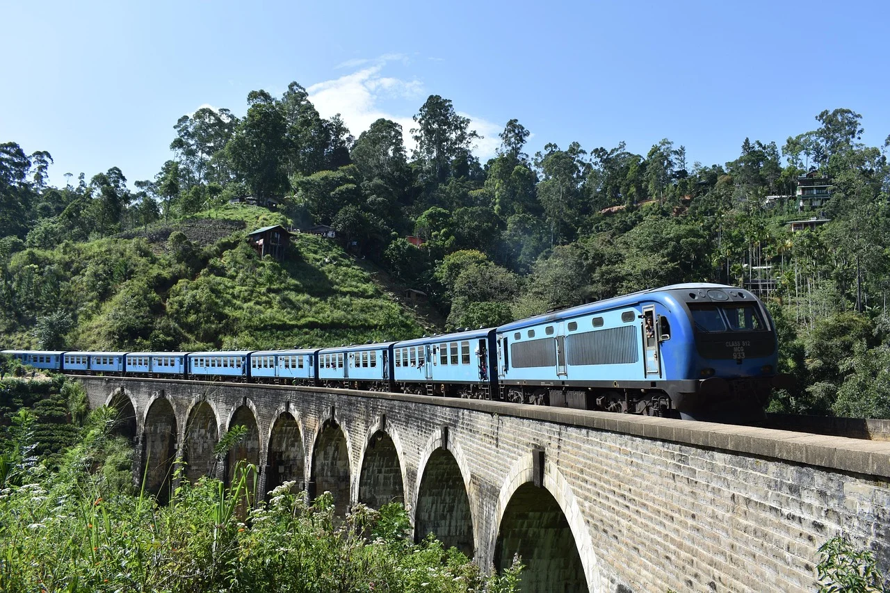 Train bleu sri-lankais franchissant le pont aux neuf arches au milieu de la végétation, près d'Ella.