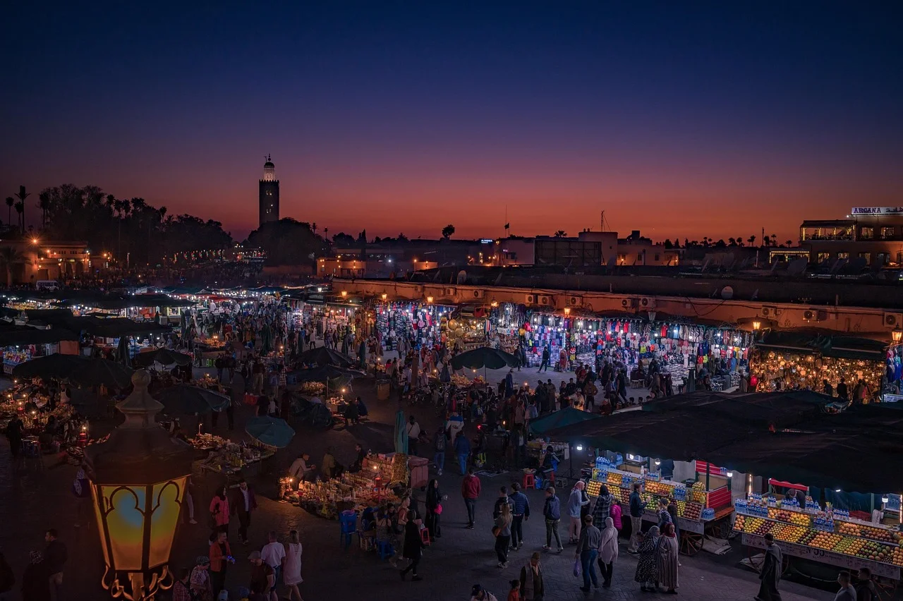La place Jemaa el-Fna à Marrakech au crépuscule, étals éclairés et minaret de la Koutoubia en silhouette