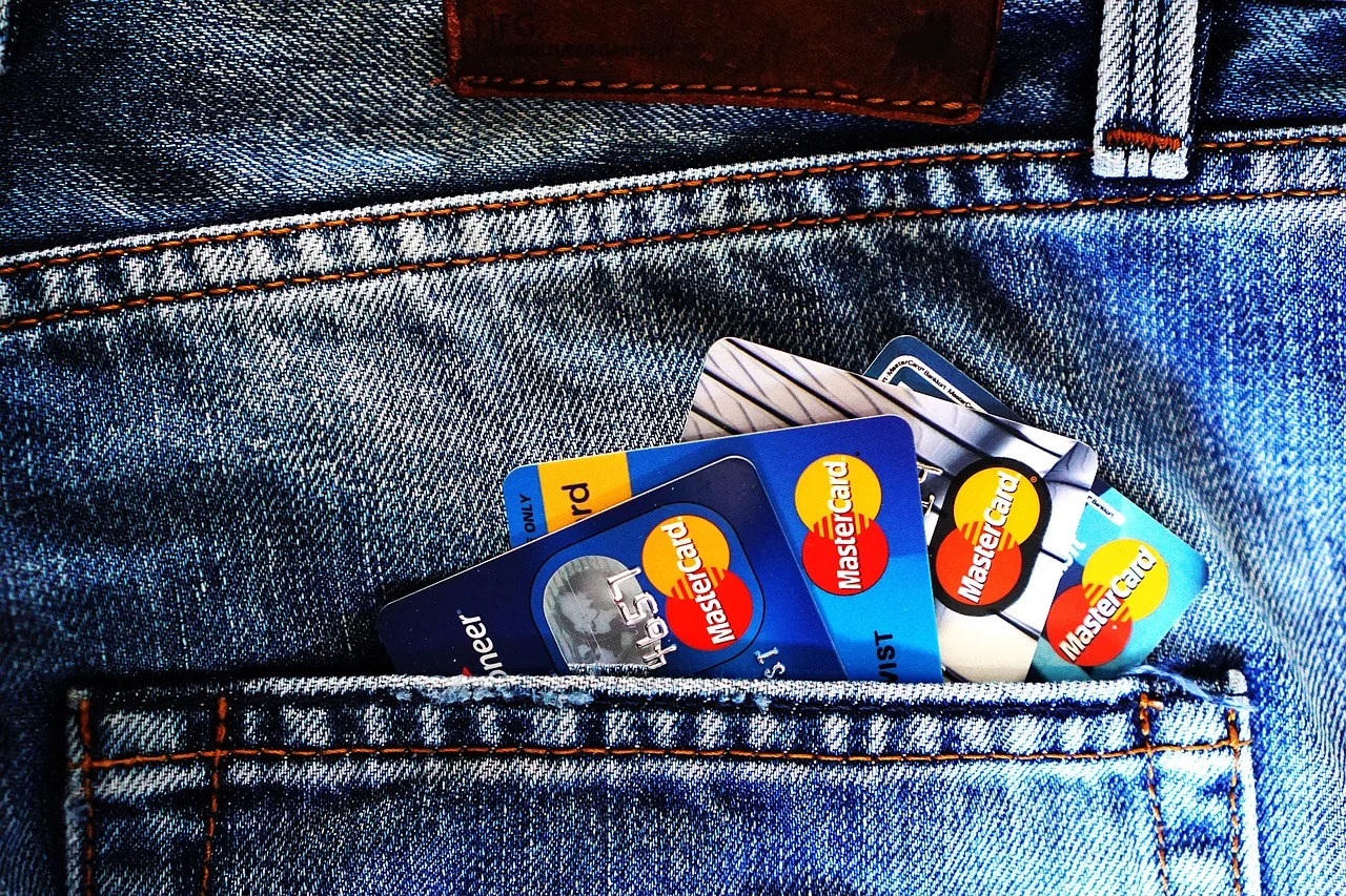 Plusieurs cartes bancaires Mastercard dépassant de la poche arrière d'un jean