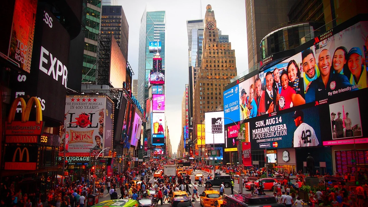 Times Square à New York en plein jour, écrans publicitaires géants, taxis jaunes et foule sur la chaussée