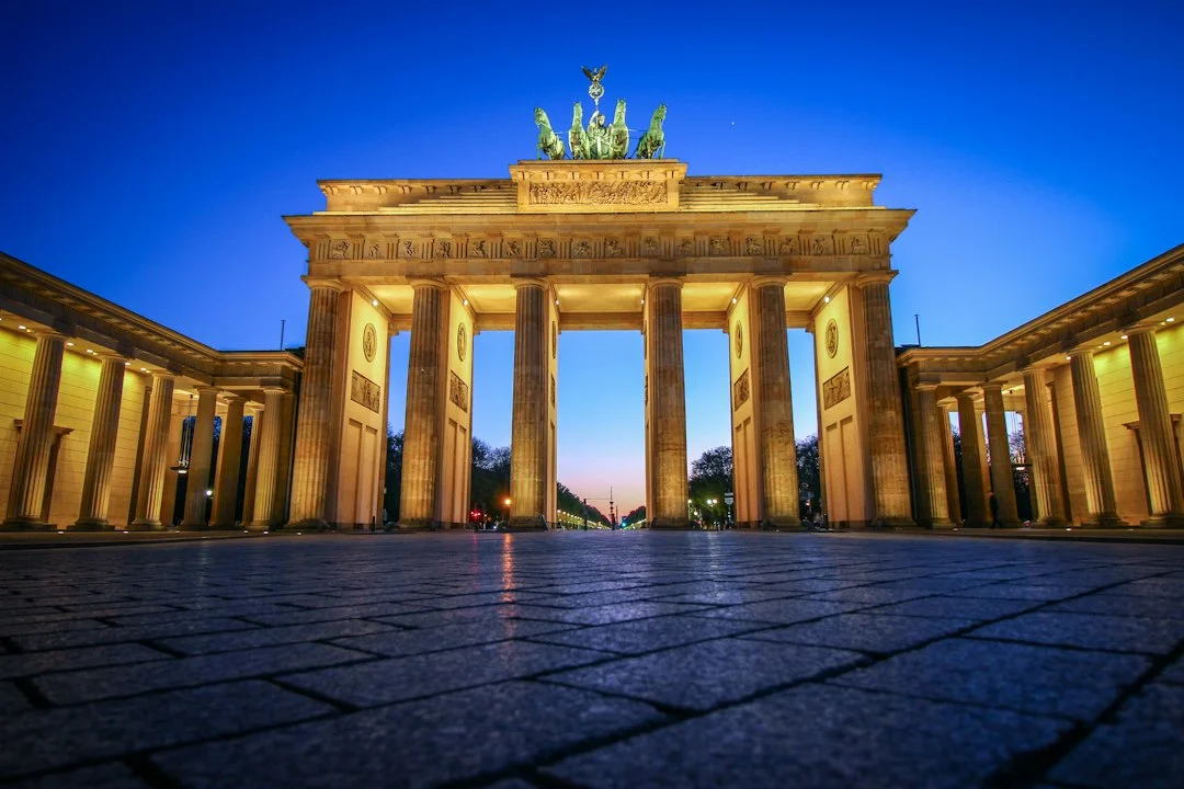 Porte de Brandebourg illuminée à l'heure bleue, vue depuis le pavé de la Pariser Platz à Berlin
