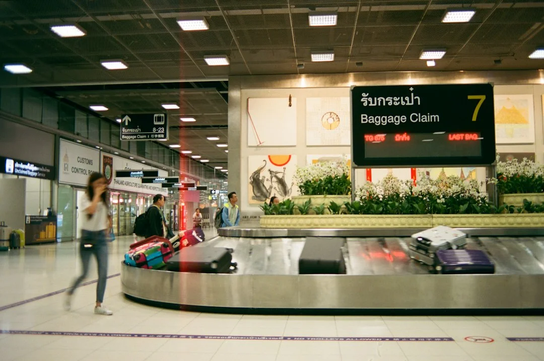 Tapis de livraison des bagages d'un aéroport avec quelques valises, sous un panneau « Baggage Claim 7 » affichant « Last bag ».